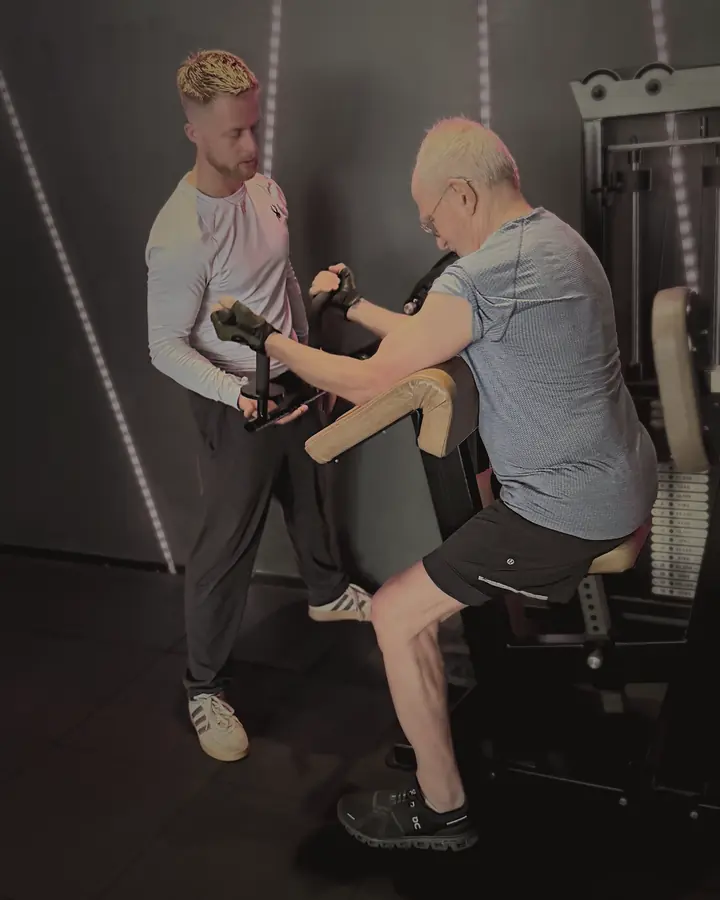 A coach cueing a member at the preacher curl